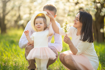 Cheerful family walks in the park with the rays of the sun. Springtime mood blooming gardens