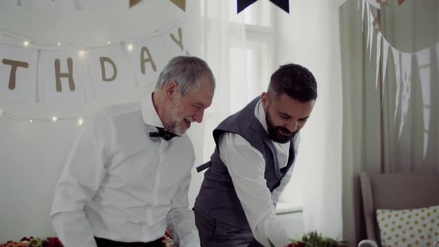 Two men with bows setting a table for an indoor party, talking.