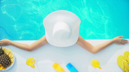 Fototapeta na wymiar Lady in summer hat relaxing in swimming pool under hot tropical sun, vacation