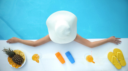 Young female enjoying summertime, sunbathing in swimming pool, luxury hotel