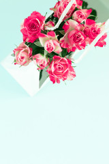Flowers composition minimal. Pink rose flowers in gift bag on pastel mint background. Flat lay, top view, copy space