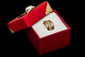 Golden wedding rings in red present box on black background
