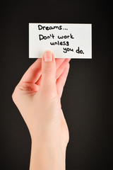 Motivation text on a card in woman  on a black background.