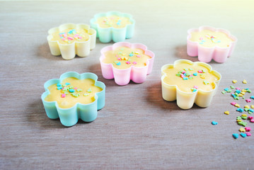 Dough is poured into baking tin. Rows of colorful cups. Muffins preparation at home.
