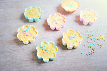 Dough is poured into baking tin. Rows of colorful cups. Muffins preparation at home.