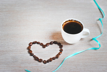 Coffee beans as a heart. cup of coffee and heart of coffee beans. Label free space.