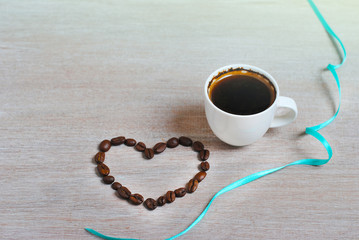 Coffee beans as a heart. cup of coffee and heart of coffee beans. Label free space.