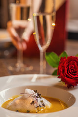 carrot and chestnut creamy soup served on white plate with wine glass, romantic time on valentines day