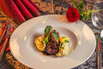 baked beef with baby patizone, sauce and spinach served on white plate with flowers and champagne, romantic time on valentines day