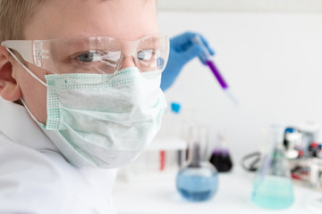 Science school, Workshop. A teenager boy conduct chemical experiments with tubes. On the table is a robot. STEM and STEAM education. Science and technology. Chemistry lab.