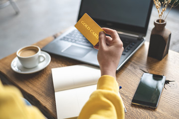Woman holding plastic card in hands against blurred laptop