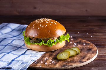 homemade hamburger with beef and cucumbers on wooden background