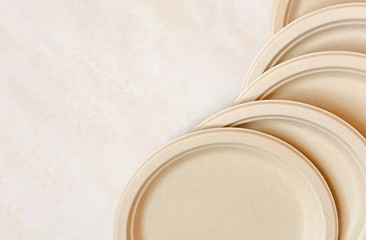 Stack of natural plant paper plates on paper background. Plastic free concept. Copy space