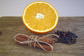 Spices and sliced fresh orange on a wooden table. Ripe orange, Cinnamon sticks and cloves on wooden background close up.