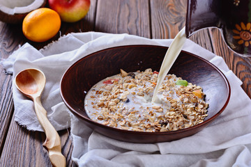 Healthy and tasty breakfast made from muesli with fruit pieces is being filled with milk