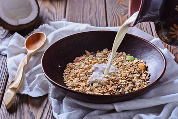 Healthy and tasty breakfast made from muesli with fruit pieces is being filled with milk
