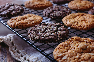 Thin, tasty, crunchy chocolate and caramel cookies on a black metal grid, closeup