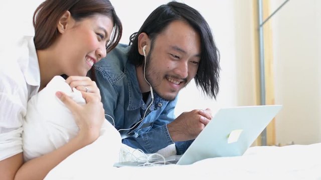 lovey couple marry asian  family enjoy weekend on bed with good movie from laptop home background