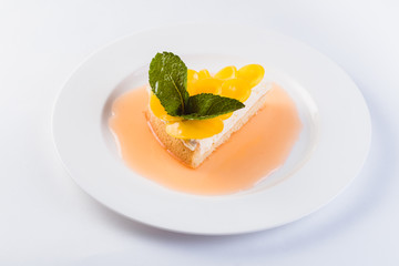 Peach cheesecake on a white plate on a light background (close)