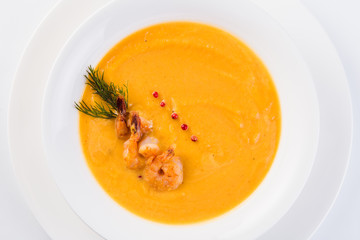 Fresh Creamy seafood soup with shrimps on a white plate on a light background (close top view)
