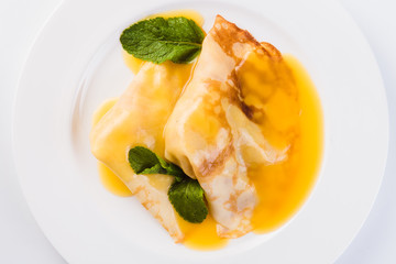 Two pancakes with honey on a white plate on a light background (close top view)
