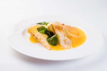 Two pancakes with honey on a white plate on a light background (close)