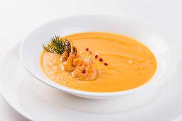 Fresh Creamy seafood soup with shrimps on a white plate on a light background (close)