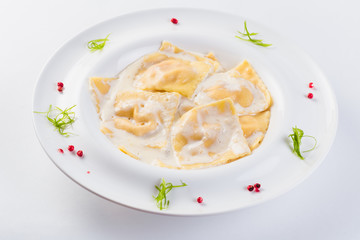 Ravioli stuffed on a white plate on a light background (close)
