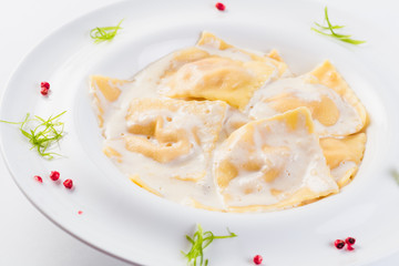 Ravioli stuffed on a white plate on a light background (close)