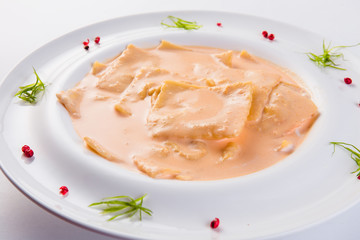 Ravioli stuffed on a white plate on a light background (close)