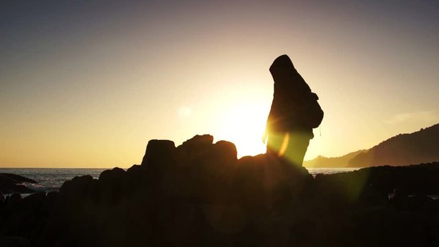 Some people relax on the rock in sea sunset over the sunlight