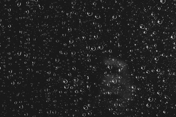 Dirty window glass with drops of rain. Atmospheric monochrome dark background with raindrops. Droplets and stains close up. Detailed transparent texture in macro with copy space. Night rainy weather.