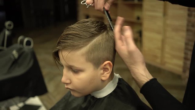The hairdresser made a stylish haircut for a little boy in barber shop