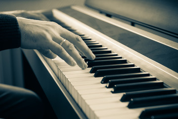 Hands of a man playing the electric piano.