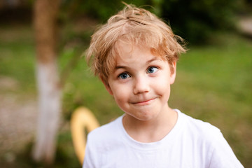 Blonde smiling boy with strabismus in warm park - obrazy, fototapety, plakaty