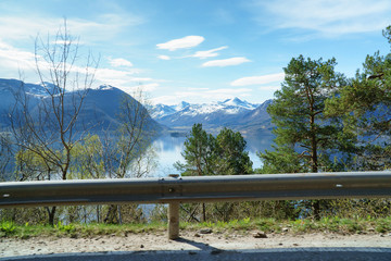 Fototapeta na wymiar Norwegian spring landscape, view from road side near fjord, scenic mountains and blue sky at background.