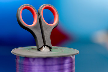 scissors and purple washi tape at blurred multicolored background. copy space. selective focus. handiwork and art creativity. for design and decor
