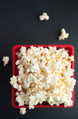 Popcorn in a red container on a white and black background. Snacks for the film.