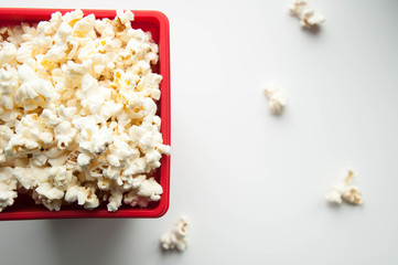 Popcorn in a red container on a white and black background. Snacks for the film.