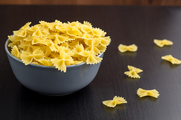 black background with italian raw farfalle or pasta in bowl with copy space