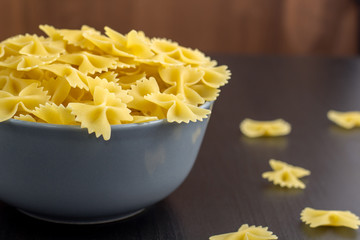 black background with italian raw farfalle or pasta in bowl with copy space