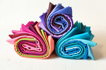 Rolled up colorful fabric swatches on white background