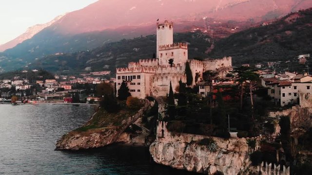 Lake Lago Garda - view of Malcesine village. Old castle on rock Italy. Aerial video sunset.