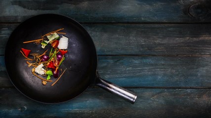 Animation. Ingredients for noodle wok in a frying pan for frying on a wooden background