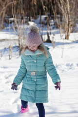 baby girl playing in snowy winter forest