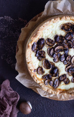 Quiche with champignons and cheese on dark brown concrete background. Savory tart with mushrooms. Cope space.