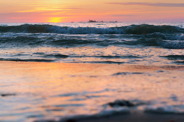 Fototapeta premium Sunset over the sea. Reflection of sunlight in the sea waves. Red and yellow sky in the rays of the sunset.