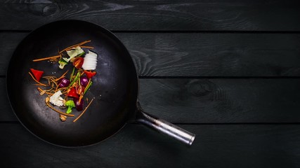 Animation. Ingredients for noodle wok in a frying pan for frying on a black wooden background