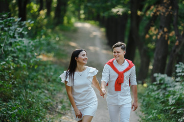 Fototapeta premium Young and happy couple walks into a green park.