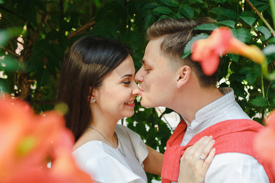 A beautiful couple kisses under a green background of nature.